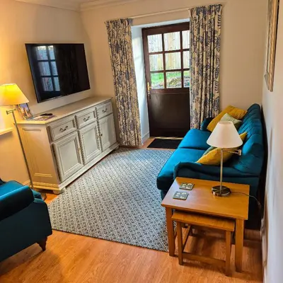 a living room with a blue couch and a tv at Loch Lomond Finnich Cottages in Drymen