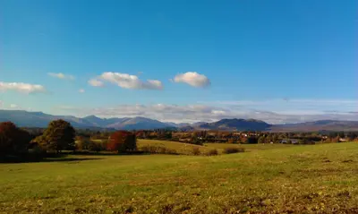 a field of green grass with mountains in the background at Ballat Smithy Cottage in Drymen