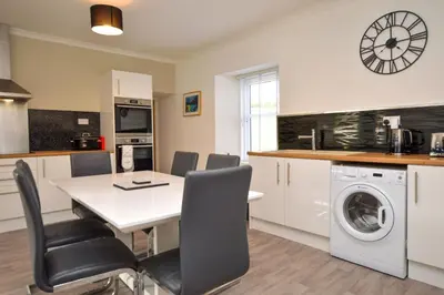 a kitchen and dining room with a table and a washing machine at Crossaig Farm House in Crossaig
