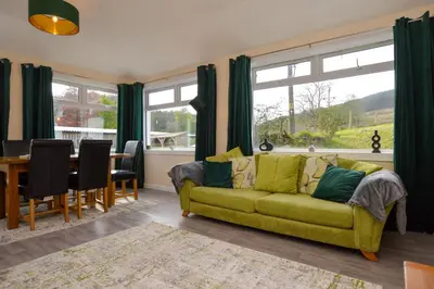 a living room with a yellow couch and a table at Crossaig Farm House in Crossaig