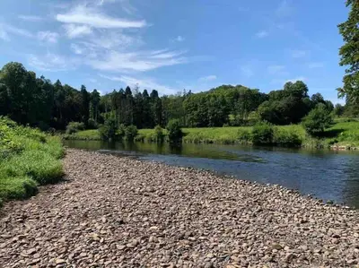 a river with rocks and trees in the background at The Orchard Apartment, Clyde Valley in Dalserf