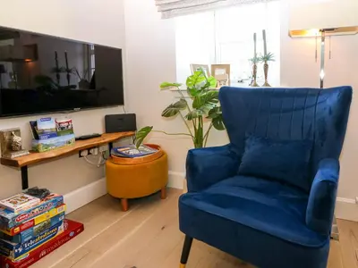 a living room with a blue chair and a table at Lyne Cottage, The Retreat in West Linton