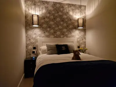 a dog sitting on a bed in a bedroom at Lyne Cottage, The Retreat in West Linton