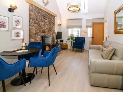 a living room with a couch and a table and chairs at Lyne Cottage, The Retreat in West Linton