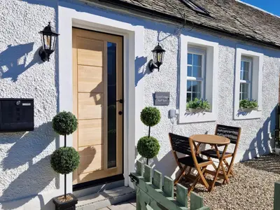 a cottage with a table and chairs in front of it at Lyne Cottage, The Retreat in West Linton