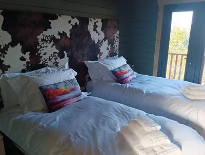 a bedroom with two beds with pillows and a wall at Ghillie's Croft Cabin, Rothesay in Rothesay