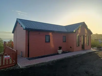 a small red house with a porch at Ghillie's Croft Cabin, Rothesay in Rothesay