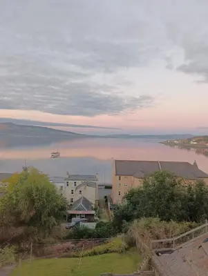 a view of a body of water with a boat in it at Ghillie's Croft Cabin, Rothesay in Rothesay