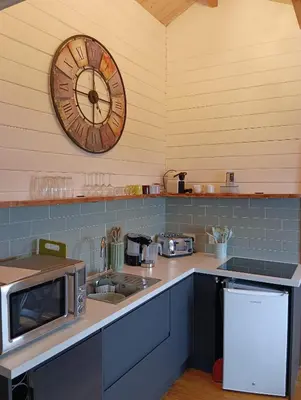 a kitchen with a clock on the wall and a sink at Ghillie's Croft Cabin, Rothesay in Rothesay