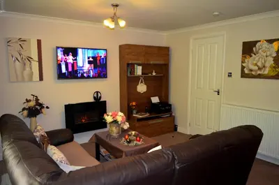 a living room with a leather couch and a tv at Double room in riverside apartment in Glasgow