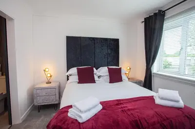 a bedroom with a large white bed with a red blanket at Modern 3 Bed Flat Balloch in Jamestown