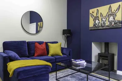 a living room with a blue couch and a mirror at Braelochan Stay in Balloch