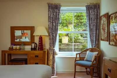 a bedroom with a bed and a desk and a window at The Pierhouse Hotel in Port Appin