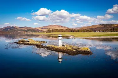 a lighthouse on an island in a body of water at The Pierhouse Hotel in Port Appin