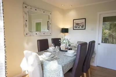 a dining room with a table with chairs and a mirror at Bruach in Balquhidder
