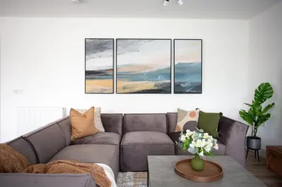 a living room with a couch and four paintings on the wall at Penthouse Apartment at Loch Lomond with 2 bedrooms in Balloch