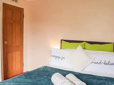 a bedroom with a bed with green and white pillows at Wallace View in Stirling