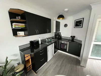a kitchen with black cabinets and a wooden floor at Elro House Holiday Let in Tillicoultry
