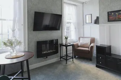 a living room with a fireplace and a chair at Carvetii - Meg's Studio - 1st Floor, Dunfermline City Centre in Dunfermline
