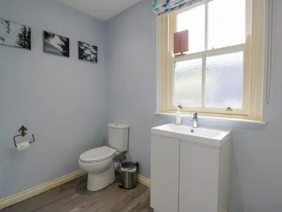 a bathroom with a toilet and a sink and a window at Kilnmark Farmhouse in Thornhill