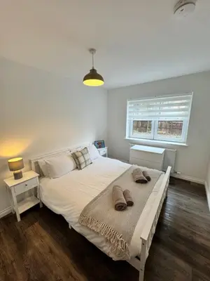 a bedroom with a large bed with two towels on it at Inchchlonaig Apartment in Bonhill