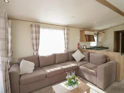 a living room with a brown couch and a kitchen at Elm in Denny