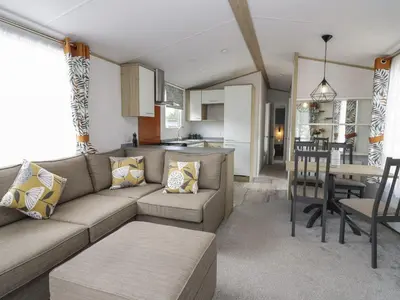 a living room with a couch and a kitchen at Ash in Denny