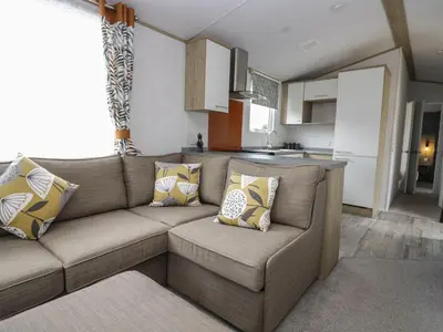 a living room with a couch and a kitchen at Ash in Denny