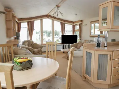 a living room with a table and a kitchen at Birch in Denny