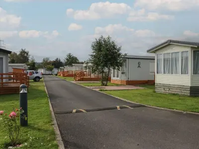 a residential street with houses and a car on the road at Yew in Denny