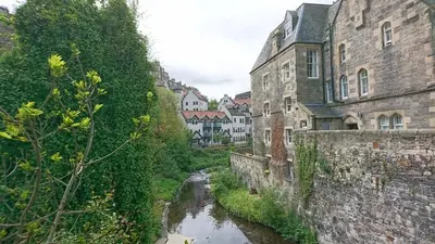 a river running through a city with tall buildings at Violet Bank Apartment New Town in Edinburgh