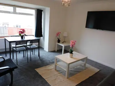a living room with a table and a tv on the wall at No 52 - Newly refurbished 3 bedroom home in East Kilbride in East Kilbride