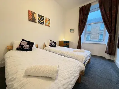 two beds in a room with a window at 2 Bed Flat - Street Parking in Glasgow