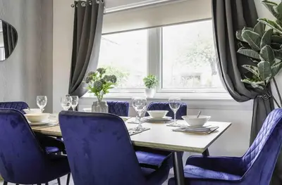 a dining room with a table with blue chairs and a window at Granby House in Livingston
