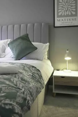 a bedroom with a bed and a table with a lamp at Granby House in Livingston