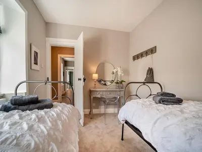 a bedroom with two beds and a table and a mirror at North Lodge in Colintraive