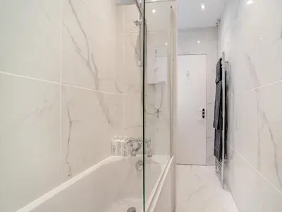 a white bathroom with a shower and a tub at North Lodge in Colintraive