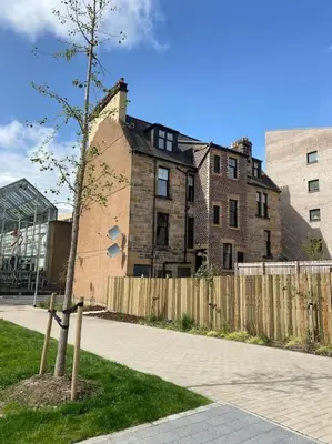 a tree in front of a building with a fence at 5 Smithhills Paisley Central GLW & Glasgow access in Paisley