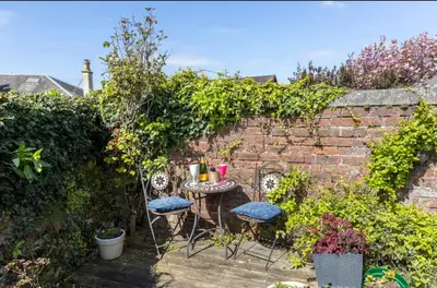 a garden with a table and chairs and a brick wall at Beach room in Ayr