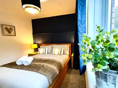 a bedroom with a bed and a potted plant at Ground Floor Flat with Free Parking & WiFi in Glasgow