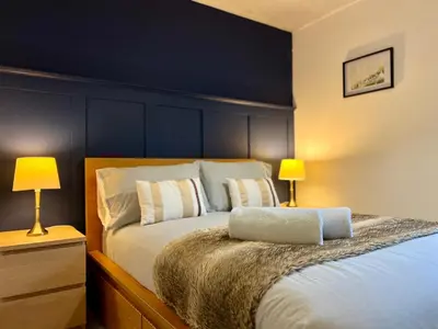 a bedroom with a large bed with two lamps at Ground Floor Flat with Free Parking & WiFi in Glasgow