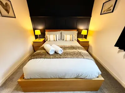 a bedroom with a bed with two pillows and two lamps at Ground Floor Flat with Free Parking & WiFi in Glasgow