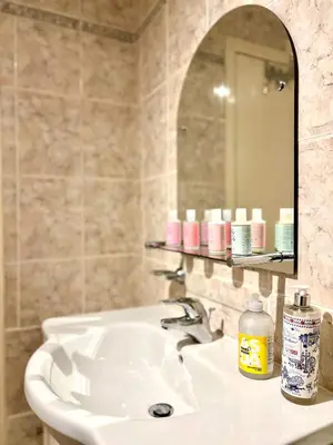 a bathroom with a white sink and a mirror at Ground Floor Flat with Free Parking & WiFi in Glasgow