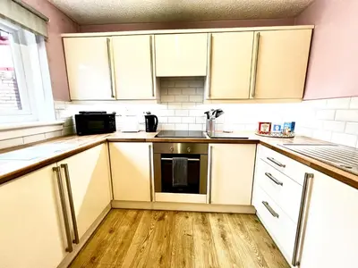 a kitchen with white cabinets and a stove top oven at Ground Floor Flat with Free Parking & WiFi in Glasgow