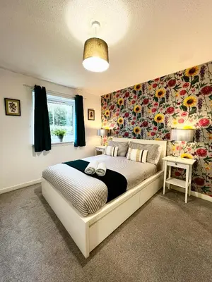 a bedroom with a large bed with a floral wall at Ground Floor Flat with Free Parking & WiFi in Glasgow