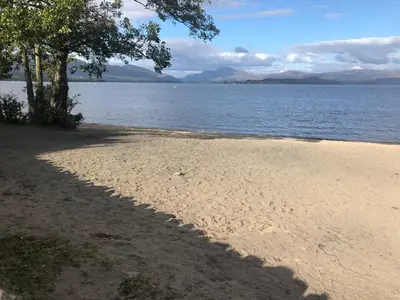 a shadow of a tree on a beach next to the water at Victorian Flat in Bonhill