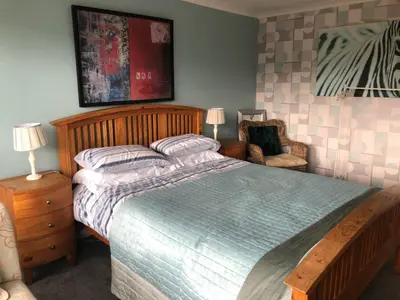 a bedroom with a large bed and a chair at Victorian Flat in Bonhill