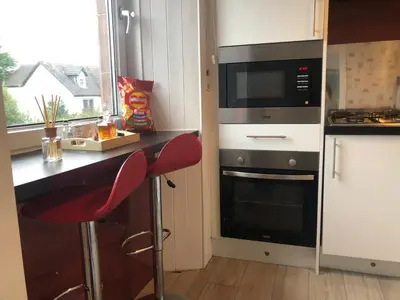 a kitchen with a counter with a microwave and a stove at Victorian Flat in Bonhill