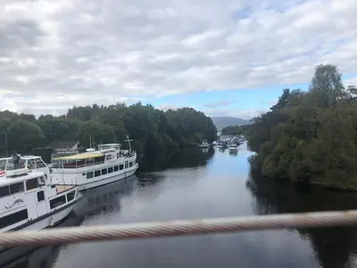 two boats are docked in a river with trees at Victorian Flat in Bonhill