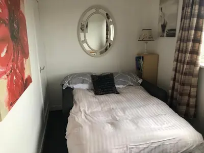 a small bed in a room with a mirror at Victorian Flat in Bonhill